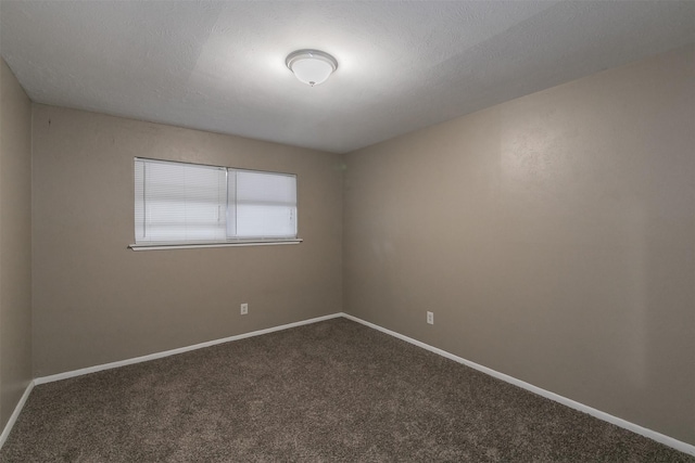 empty room featuring dark colored carpet and a textured ceiling