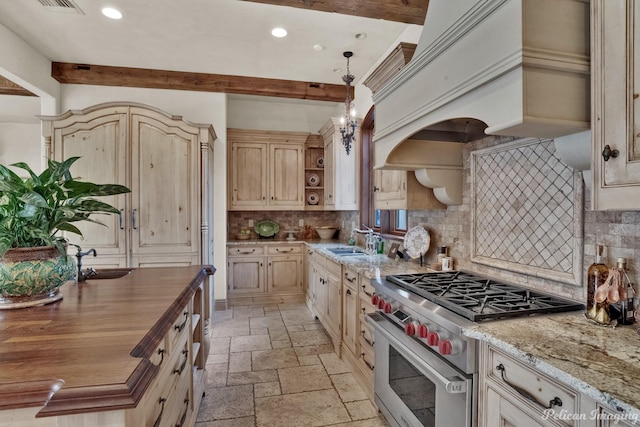 kitchen with sink, high end range, light stone counters, backsplash, and hanging light fixtures