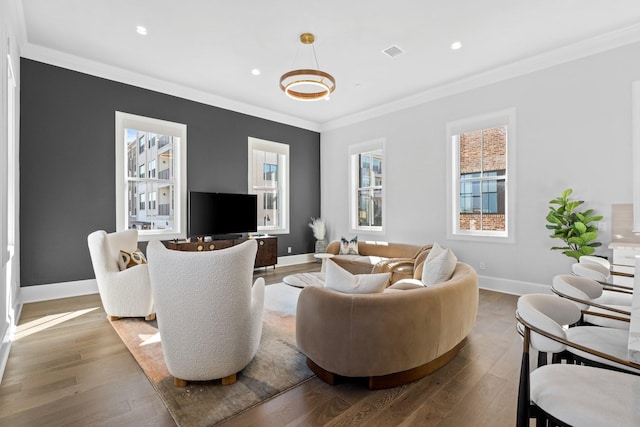 living room with wood finished floors, baseboards, visible vents, recessed lighting, and ornamental molding