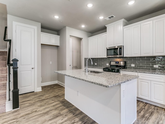 kitchen with appliances with stainless steel finishes, white cabinets, visible vents, and a sink