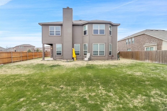 rear view of house featuring a chimney, a fenced backyard, and a lawn