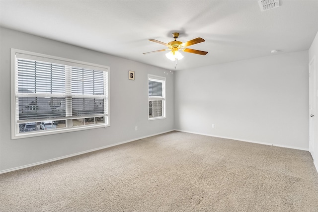 carpeted empty room featuring ceiling fan, visible vents, and baseboards