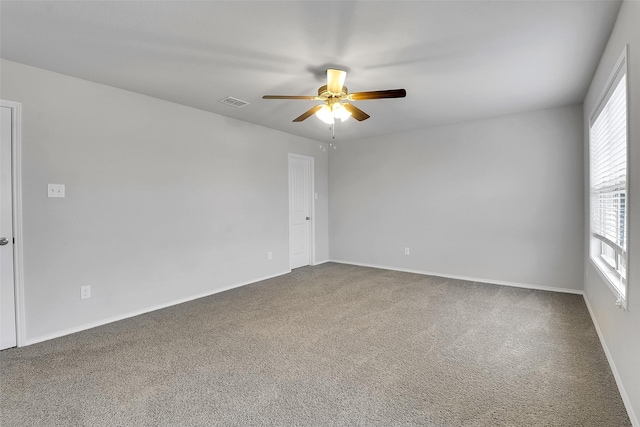 empty room featuring carpet floors, ceiling fan, visible vents, and baseboards