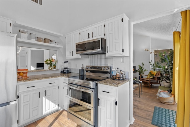 821 Dublin Dr Unit 143, Richardson, TX 75080 - kitchen featuring light stone countertops, light wood-style flooring, white cabinetry, and appliances with stainless steel finishes