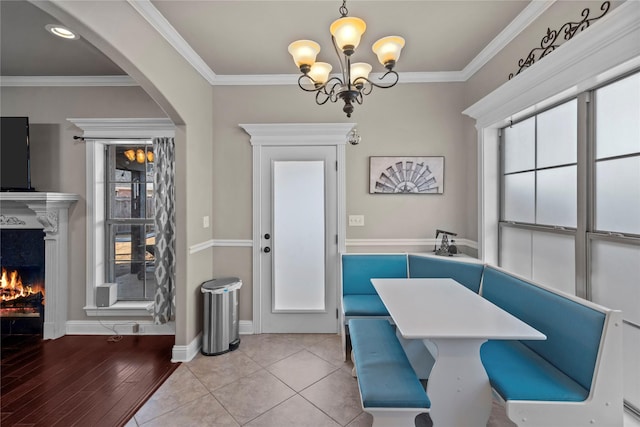 tiled dining space featuring a high end fireplace, crown molding, and a notable chandelier