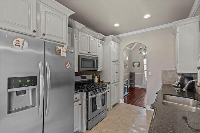 kitchen featuring tasteful backsplash, stainless steel appliances, sink, white cabinetry, and dark stone countertops