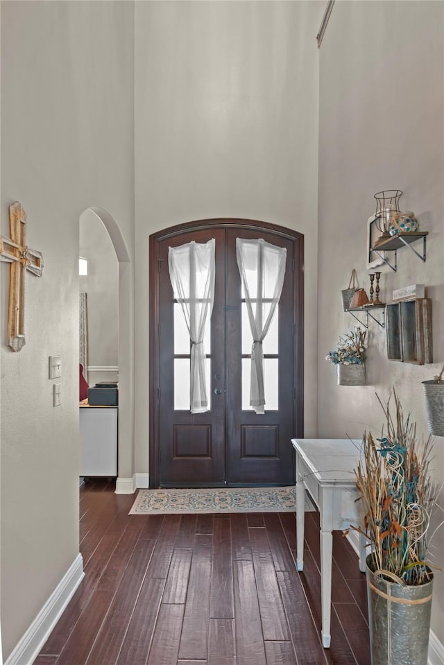 foyer entrance with french doors, dark hardwood / wood-style flooring, and a towering ceiling