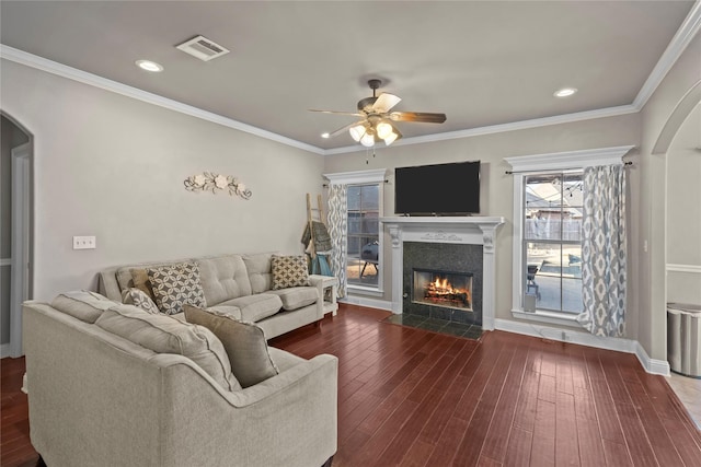 living room with a fireplace, ornamental molding, dark hardwood / wood-style floors, and ceiling fan