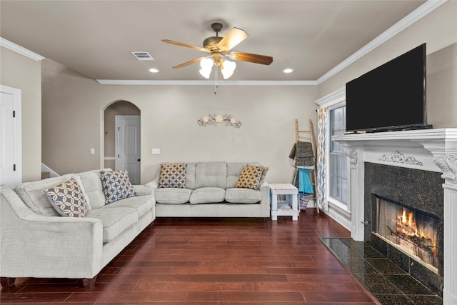 living room featuring a fireplace, dark wood-type flooring, ornamental molding, and ceiling fan