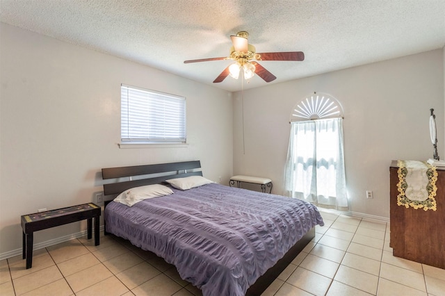 tiled bedroom with multiple windows, a textured ceiling, and ceiling fan