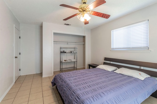 bedroom featuring ceiling fan, light tile patterned floors, a textured ceiling, and a closet