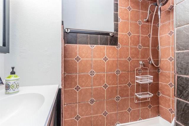 bathroom featuring a tile shower and vanity