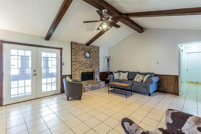 tiled living room featuring a brick fireplace, vaulted ceiling with beams, french doors, and a textured ceiling