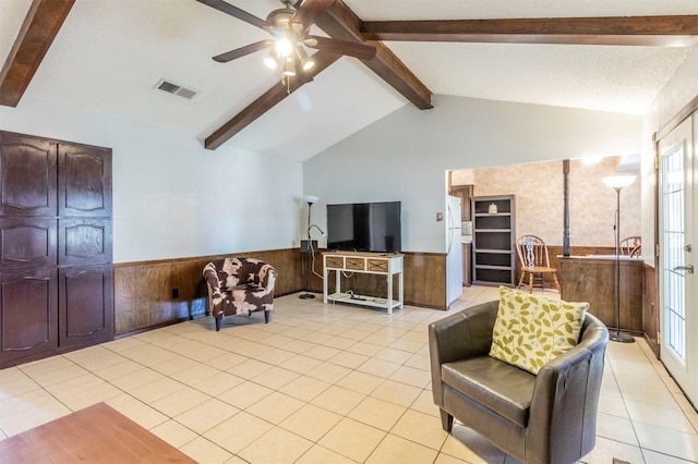 tiled living room with plenty of natural light, vaulted ceiling with beams, wood walls, and ceiling fan