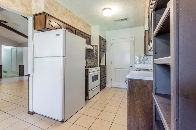 kitchen with dark brown cabinets, white appliances, a textured ceiling, light tile patterned flooring, and backsplash