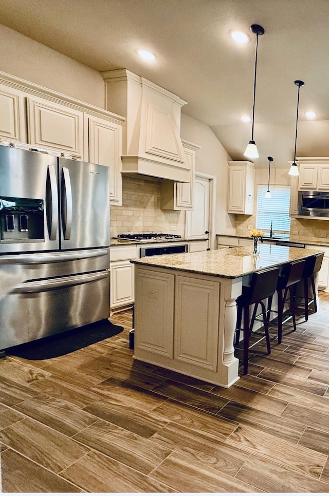 kitchen featuring tasteful backsplash, a center island with sink, custom exhaust hood, stainless steel appliances, and a sink