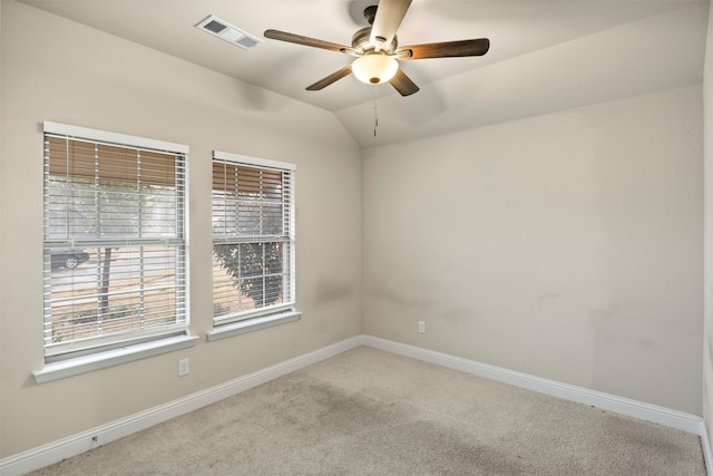 spare room with ceiling fan, vaulted ceiling, light colored carpet, and plenty of natural light