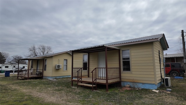 rear view of house with metal roof and a lawn