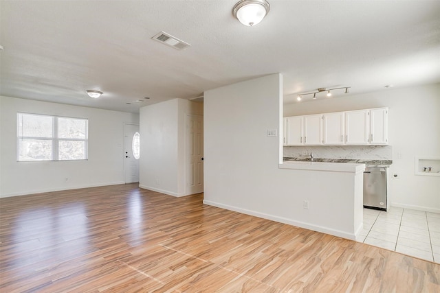 unfurnished living room with light wood-style floors, baseboards, and visible vents