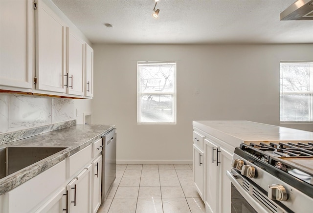 kitchen with light tile patterned floors, a textured ceiling, white cabinets, appliances with stainless steel finishes, and backsplash