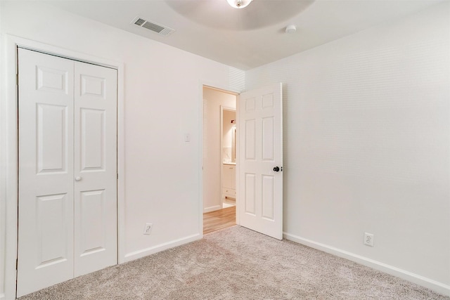 unfurnished bedroom featuring light carpet, baseboards, visible vents, a ceiling fan, and a closet