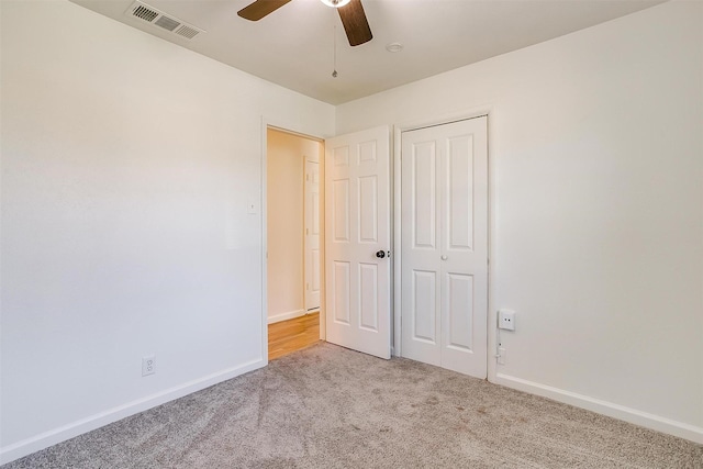 unfurnished bedroom featuring a closet, visible vents, a ceiling fan, light carpet, and baseboards