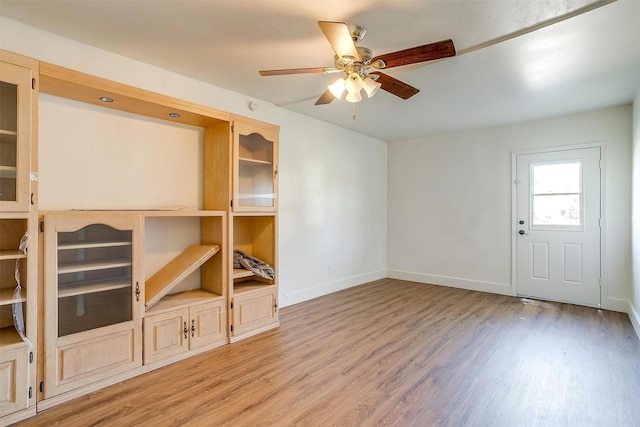 unfurnished living room featuring light wood-type flooring, baseboards, and a ceiling fan