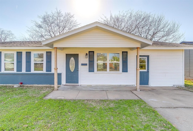 single story home with a porch, a front yard, and roof with shingles