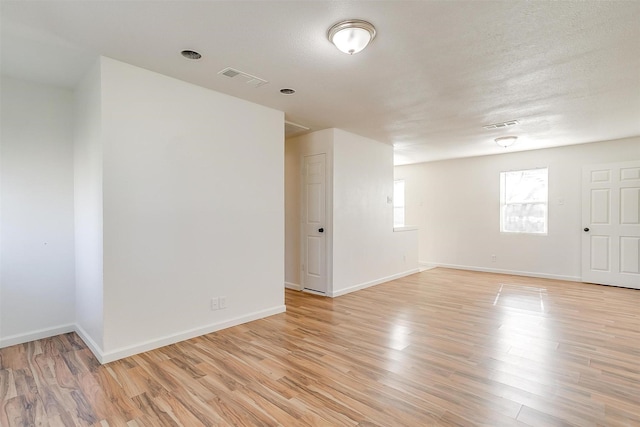 spare room featuring light wood-style flooring, visible vents, and baseboards