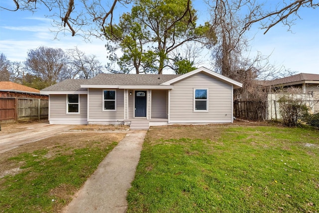 view of front of home with roof with shingles, fence, and a front yard