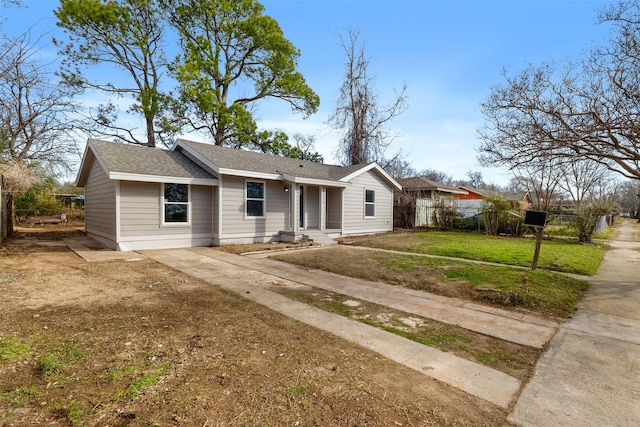 ranch-style home featuring fence, a front lawn, and roof with shingles