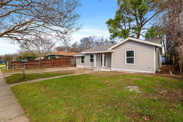 view of front of property featuring a shingled roof, fence, and a front yard