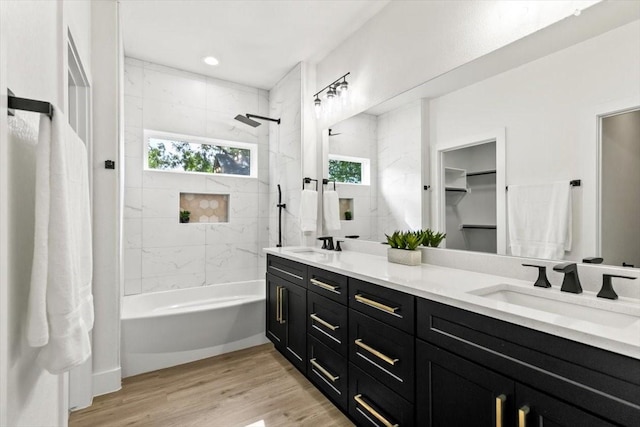 full bathroom with double vanity, shower / bath combination, a sink, and wood finished floors