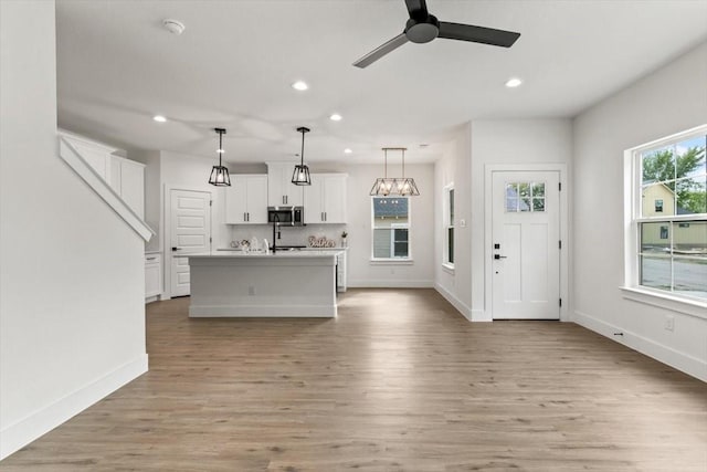 unfurnished living room with light wood finished floors, baseboards, a ceiling fan, and recessed lighting