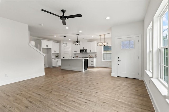 unfurnished living room featuring recessed lighting, ceiling fan, and light wood-style flooring