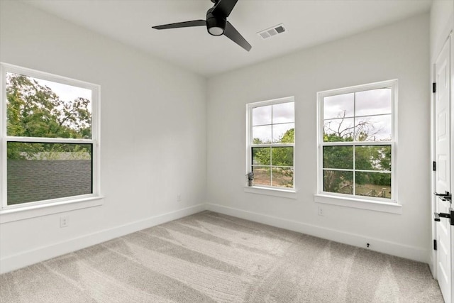 carpeted spare room featuring ceiling fan, visible vents, and baseboards