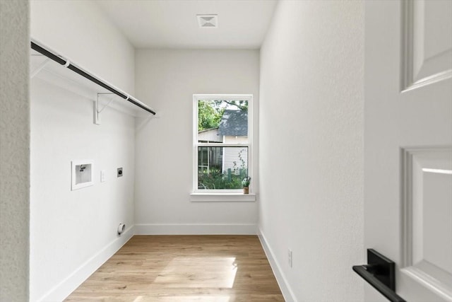 laundry area with laundry area, baseboards, light wood-style flooring, hookup for a washing machine, and electric dryer hookup