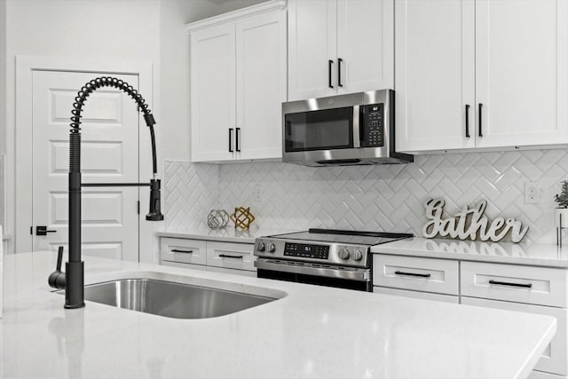 kitchen featuring a sink, stainless steel appliances, decorative backsplash, and white cabinets