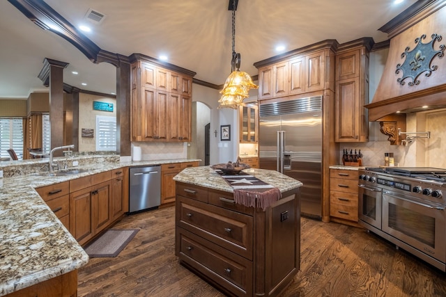 kitchen with high end appliances, crown molding, a center island, sink, and dark hardwood / wood-style floors