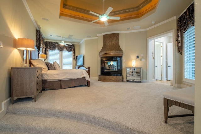 carpeted bedroom featuring a multi sided fireplace, crown molding, ceiling fan, and a raised ceiling