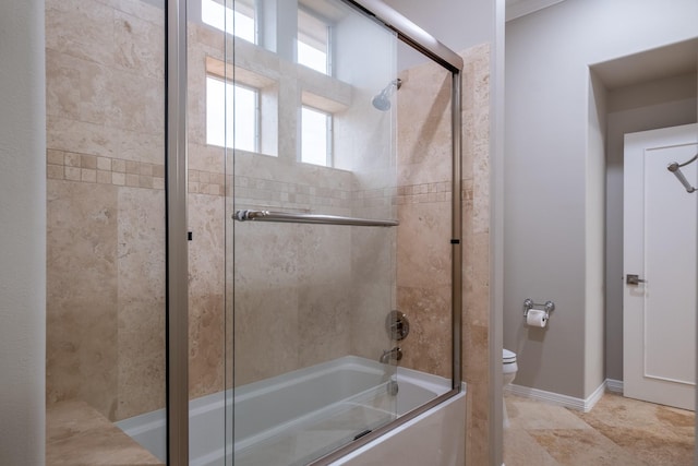 bathroom featuring toilet and bath / shower combo with glass door