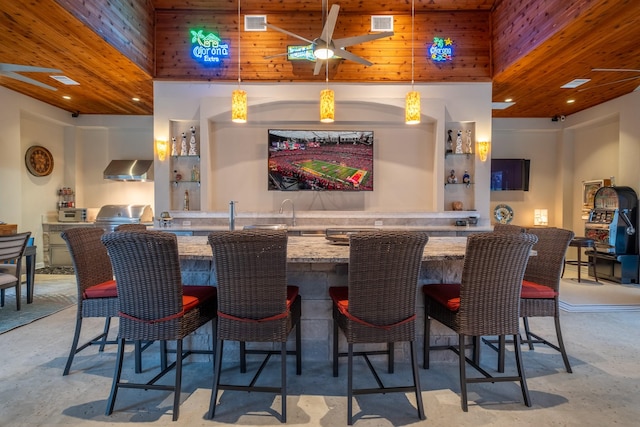 bar with wall chimney range hood and a high ceiling