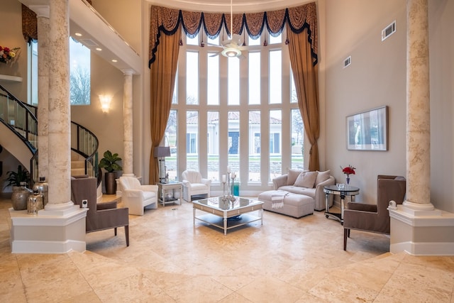 living room with a water view, decorative columns, and a towering ceiling