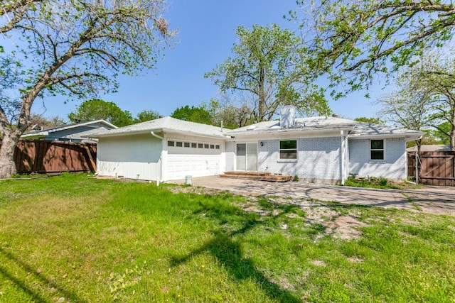 back of property featuring a garage and a lawn