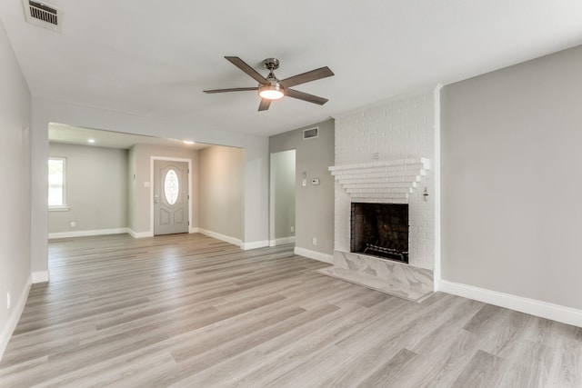 unfurnished living room featuring a brick fireplace, ceiling fan, and light hardwood / wood-style flooring