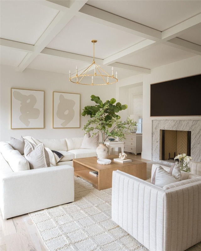 living room featuring a high end fireplace, a notable chandelier, coffered ceiling, beamed ceiling, and light wood-type flooring