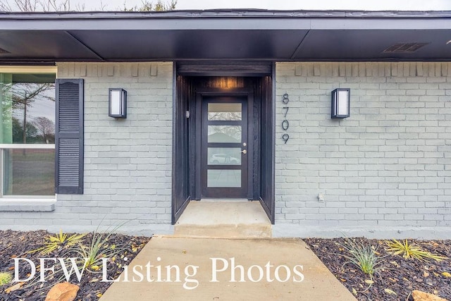 entrance to property featuring brick siding