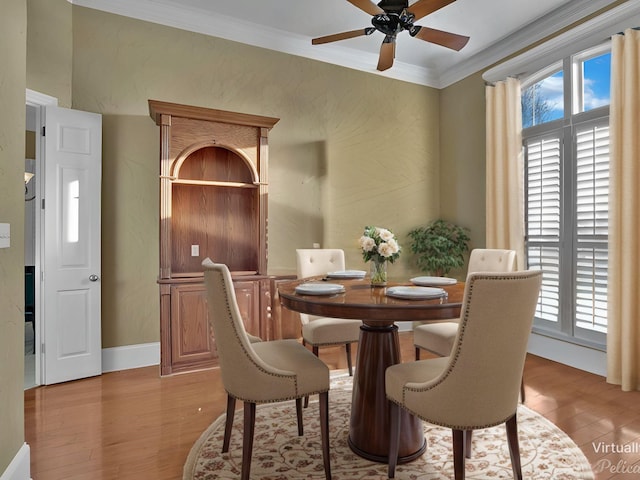 dining space with light wood-type flooring, ornamental molding, ceiling fan, and a wealth of natural light