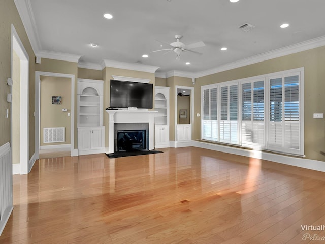 unfurnished living room featuring ceiling fan, built in shelves, crown molding, and light hardwood / wood-style floors