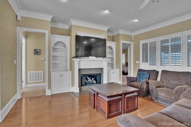 living room with light wood-type flooring, ceiling fan, built in features, and ornamental molding